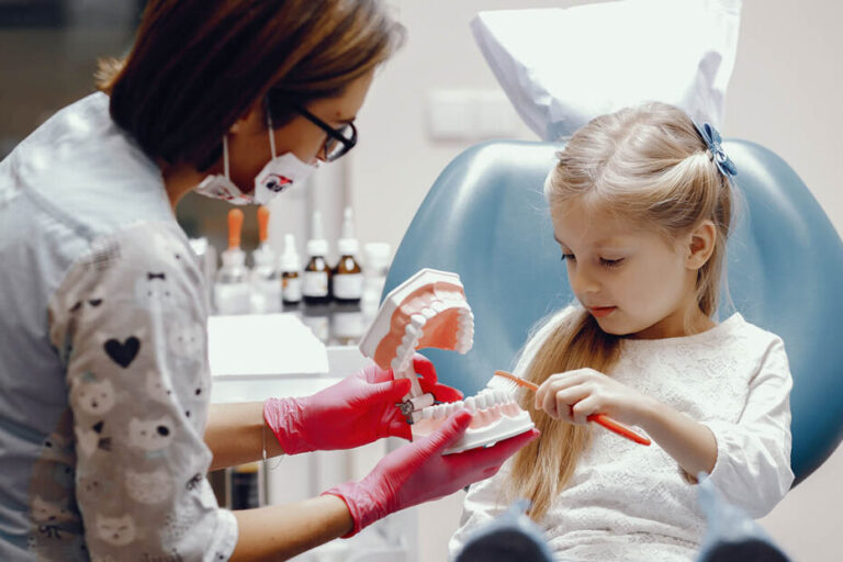 Little girl talking to the dendist. Child in the dentist's office. Woman in a uniform